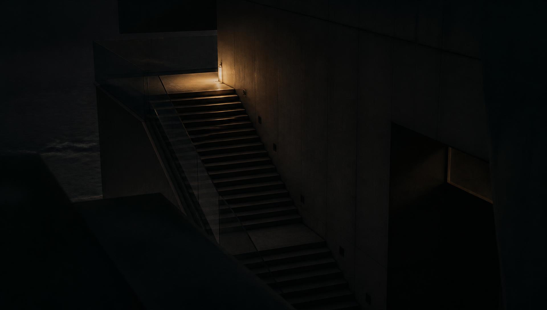 Dimly lit modern staircase ascending through a concrete structure